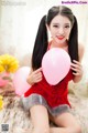 A woman in a red dress holding a pink balloon.