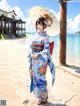 A woman in a kimono standing on a beach holding an umbrella.