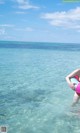 A woman in a pink bikini holding an inflatable ring in the ocean.