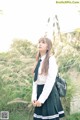 A woman in a school uniform standing in the grass.