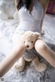 A woman sitting on a bed holding a teddy bear.