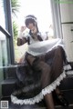 A woman in a black and white dress sitting on a window sill.