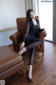 A woman sitting on a brown leather chair in a room.